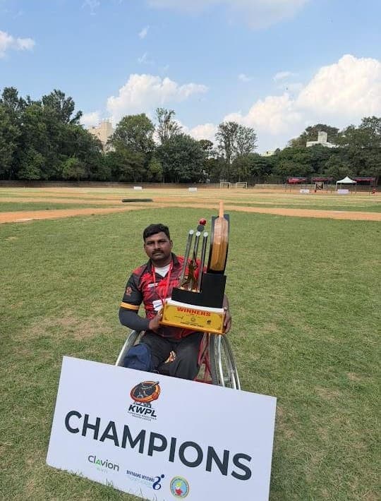Abraham with a trophy behind a KWPL Champions sign