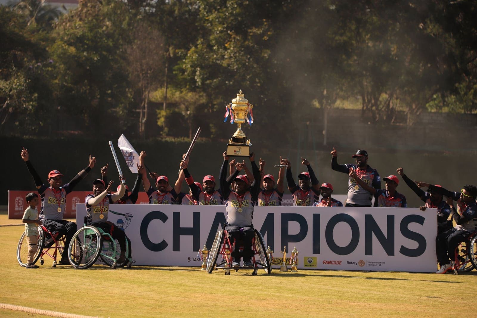 The team celebrating with a trophy behind a Champions banner