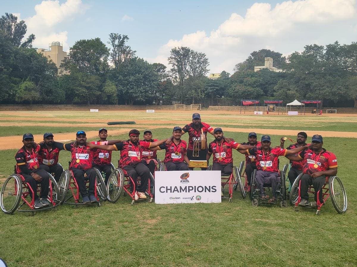 Sunil's team in wheelchairs celebrating behind a Champions banner