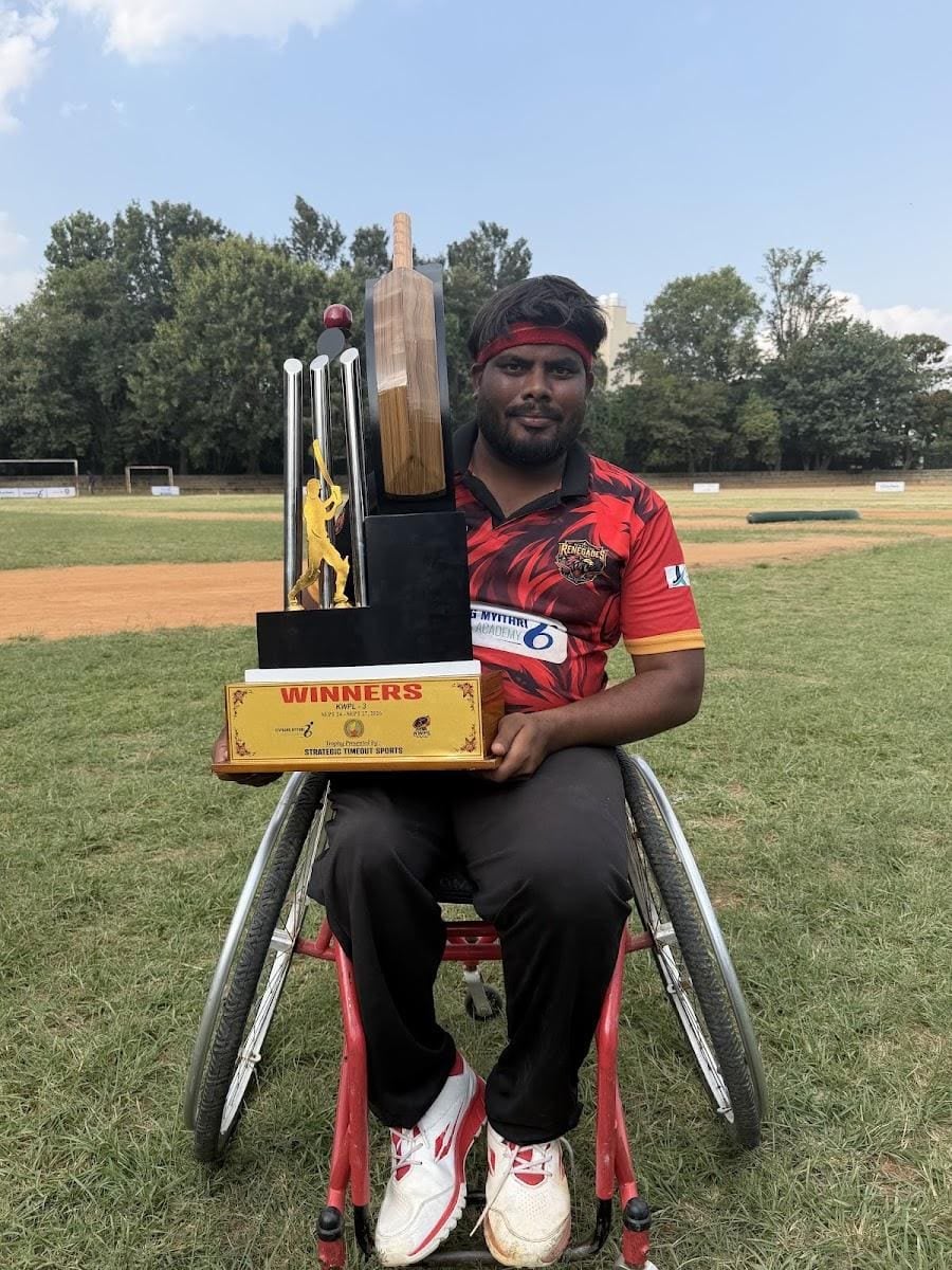 Bavaraj in a sports wheelchair with a winners' trophy on the ground
