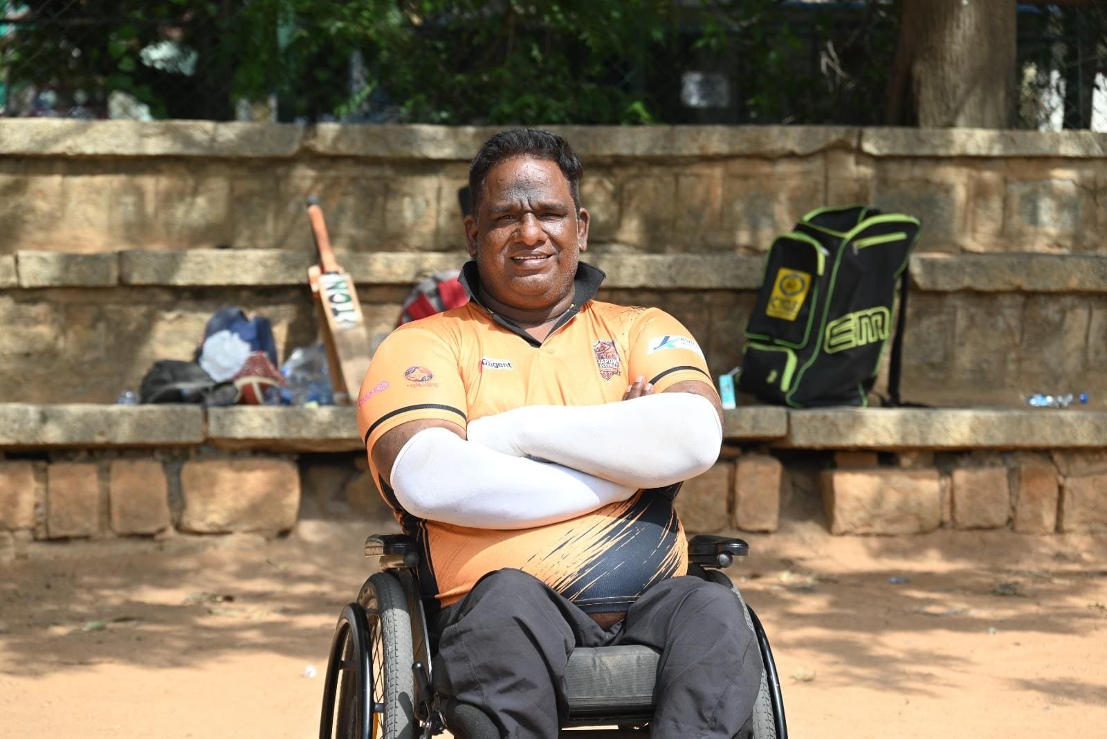 G Ramanathan seated in a sports wheelchair with arms crossed, beside a kit bag