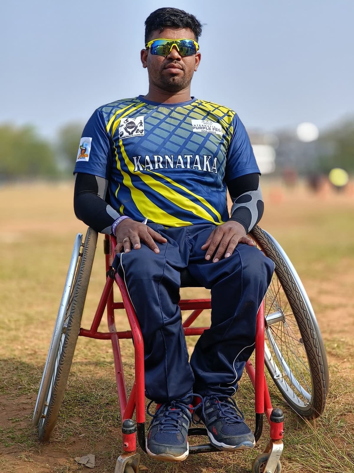 Kalla Praveen Kumar seated in a sports wheelchair wearing a Karnataka jersey