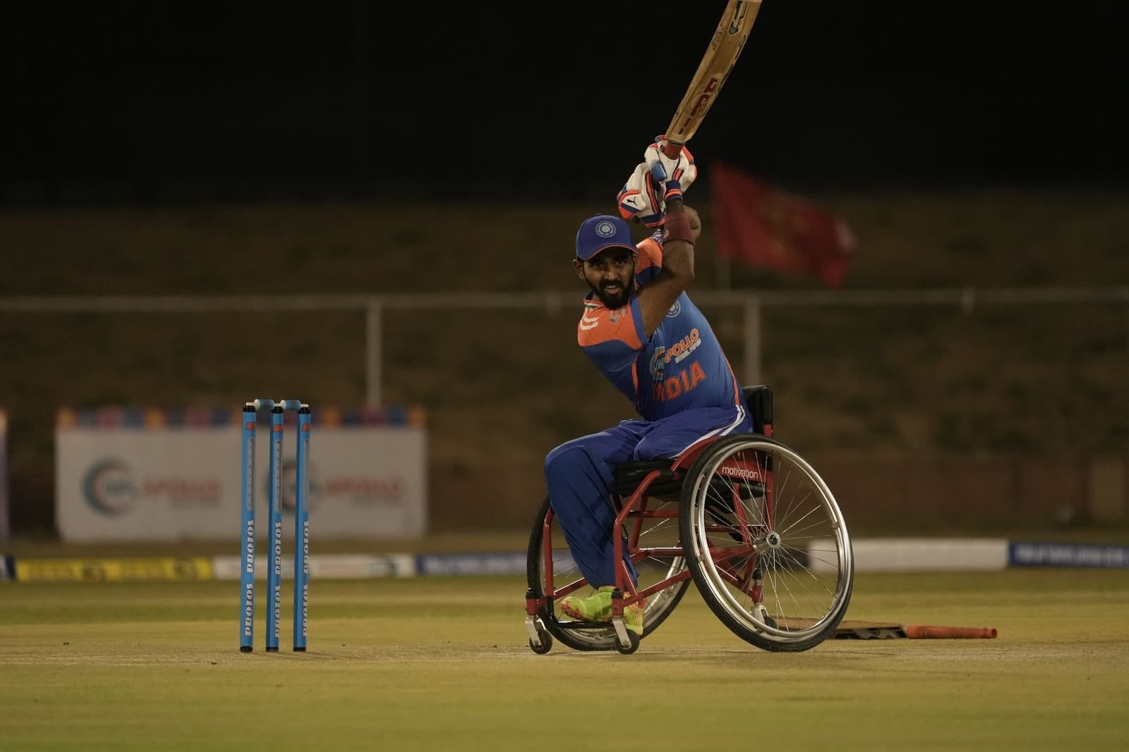 Sagar BR playing a shot in an India kit during a floodlit wheelchair cricket match